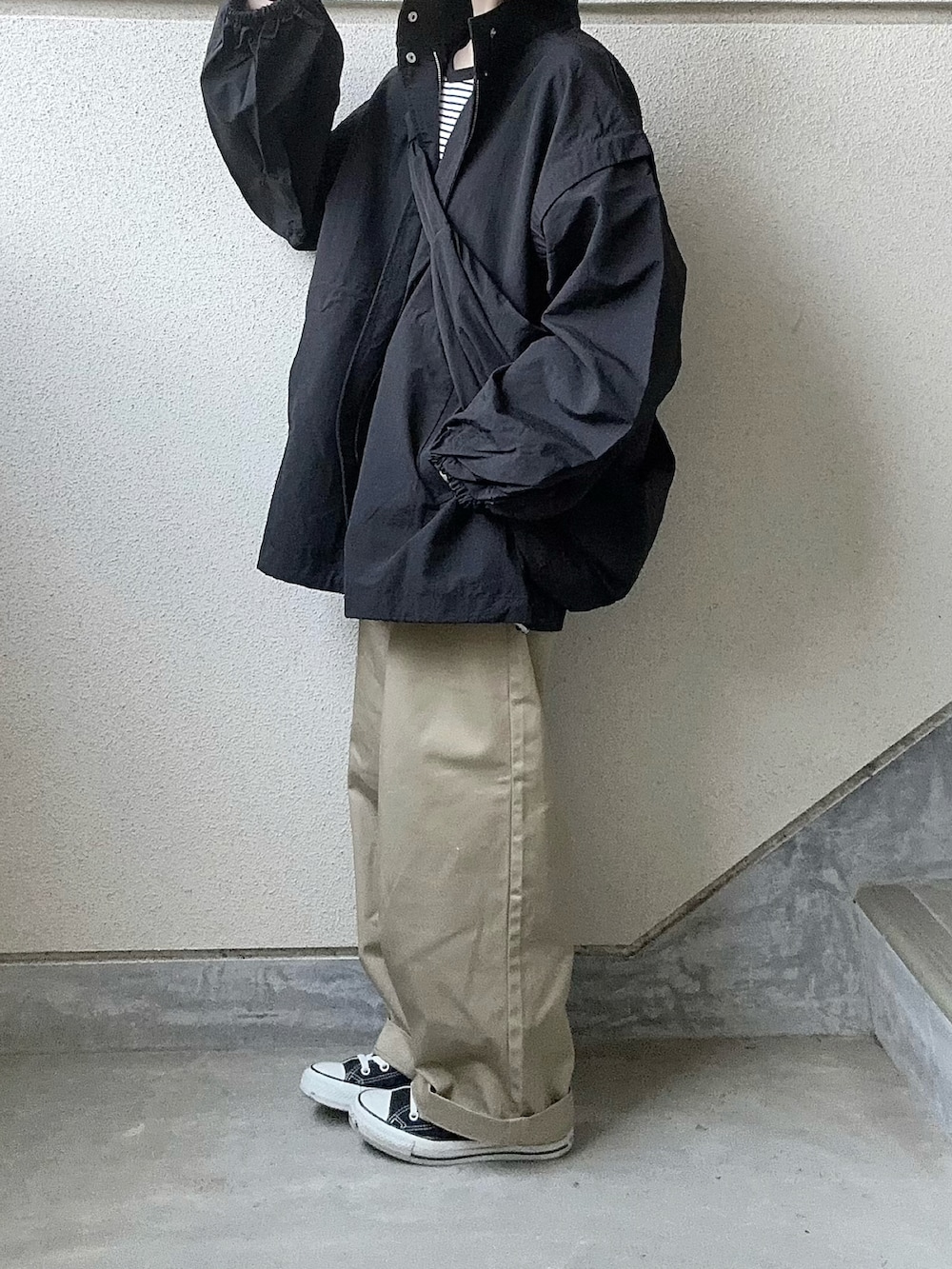 ブラック系のブルゾン、ブラック系のTシャツ/カットソー、ベージュ系のチノパンツを着用したレディースの春コーディネートの4枚目の写真