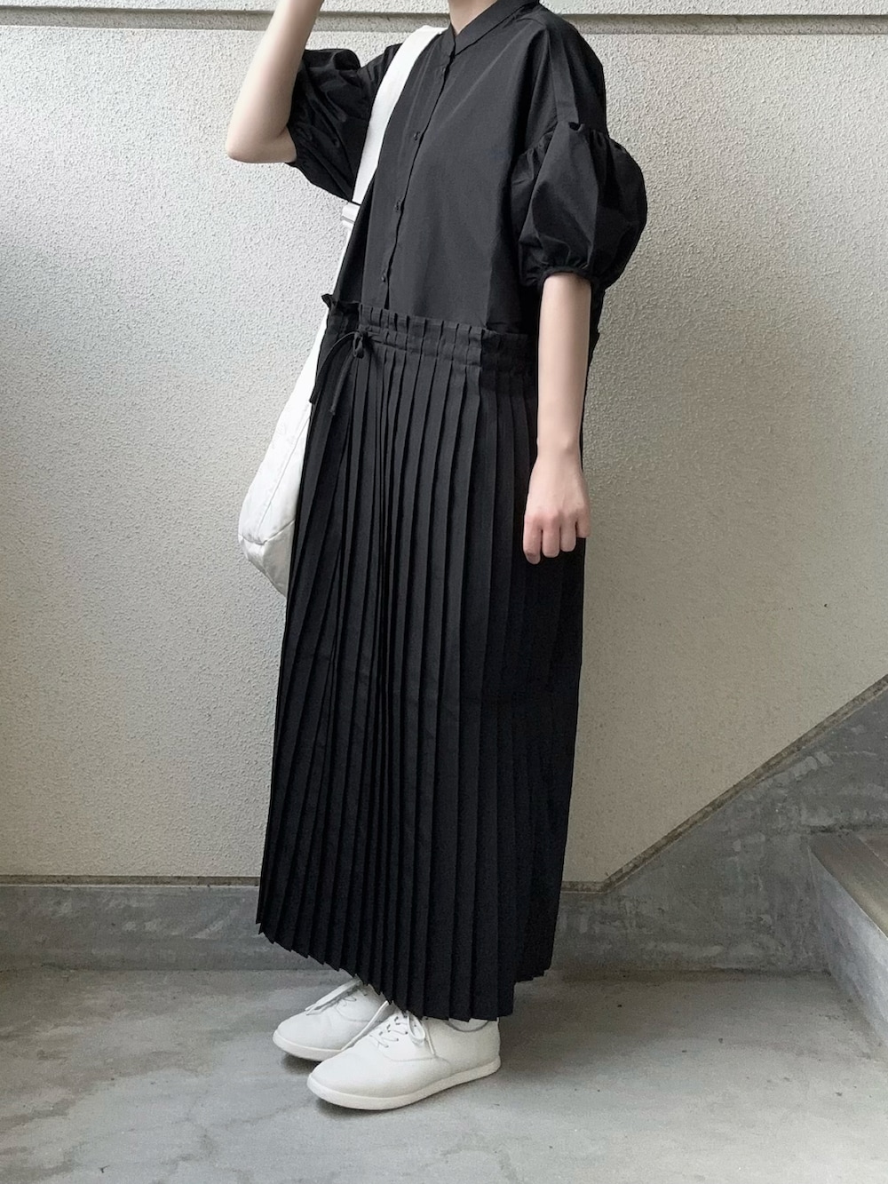 ブラック系のワンピース、ホワイト系のショルダーバッグ、ホワイト系のスニーカーを着用したレディースの春コーディネートの3枚目の写真