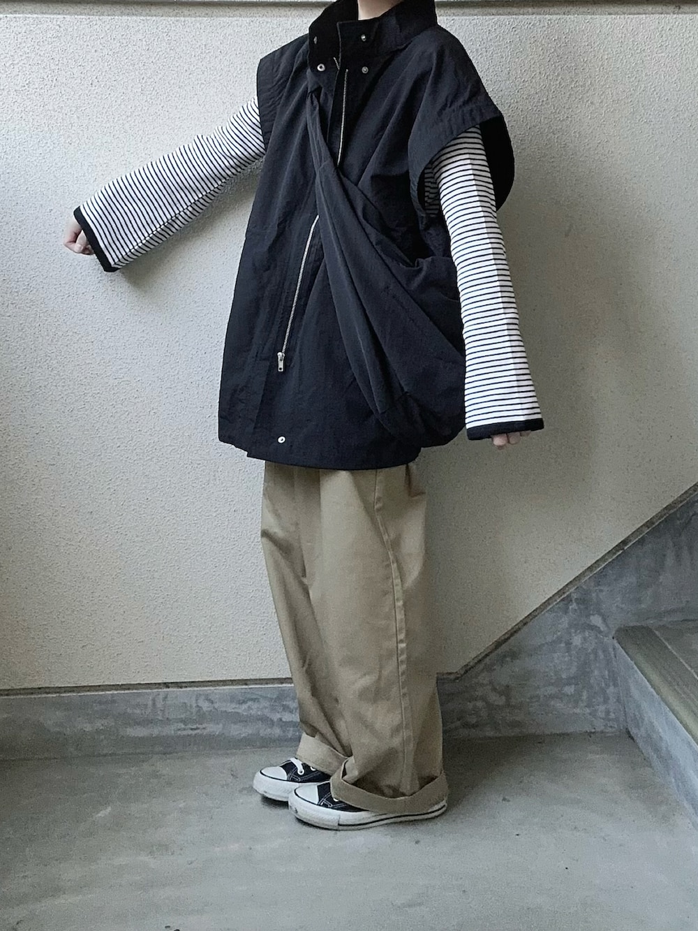 ブラック系のブルゾン、ブラック系のTシャツ/カットソー、ベージュ系のチノパンツを着用したレディースの春コーディネートの2枚目の写真