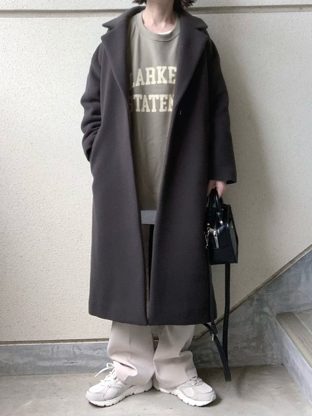 グレー系のチェスターコート、グリーン系のスウェット、グレー系のスニーカーを着用したレディースの秋コーディネートの2枚目の写真