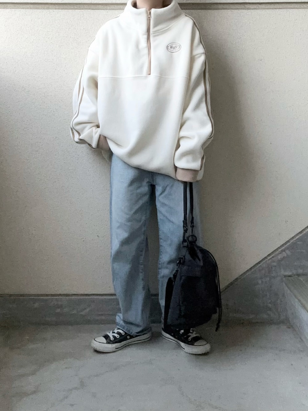 ホワイト系のスウェット、ブラック系のショルダーバッグ、ブルー系のデニムパンツを着用したレディースの秋コーディネートの4枚目の写真