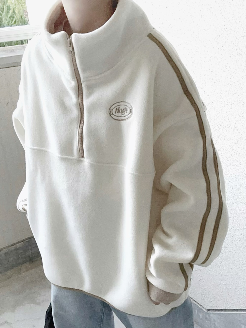 ホワイト系のスウェット、ブラック系のショルダーバッグ、ブルー系のデニムパンツを着用したレディースの秋コーディネートの5枚目の写真