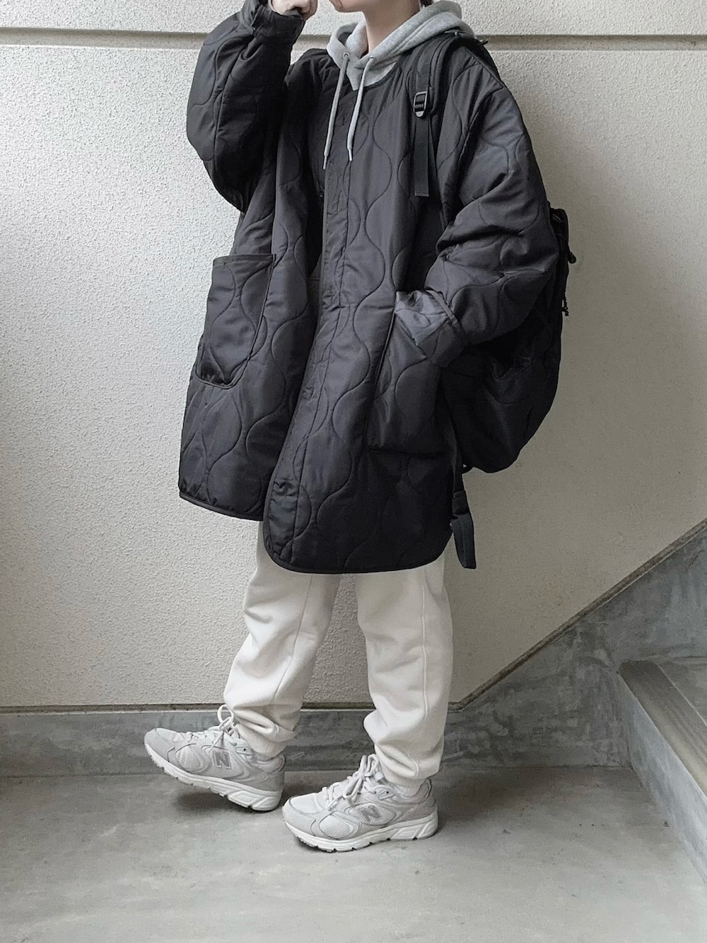 ブラック系のノーカラーコート、グレー系のパーカー、ホワイト系のスウェットパンツを着用したレディースの冬コーディネートの4枚目の写真
