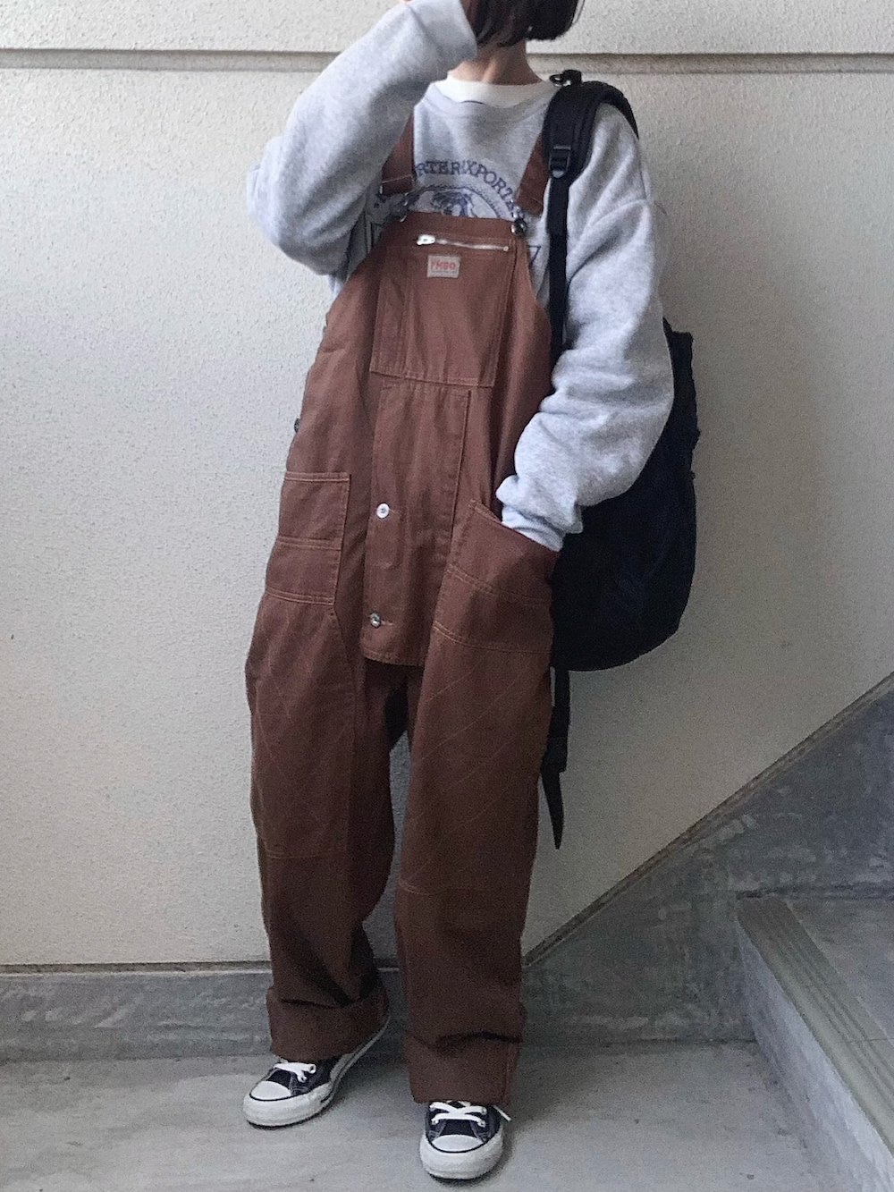 ブラウン系のサロペット/オーバーオール、グレー系のスウェット、ブラック系のスニーカーを着用したレディースの冬コーディネートの5枚目の写真