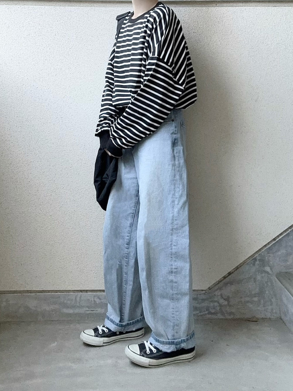 ブラック系のTシャツ/カットソー、ブラック系のショルダーバッグ、ブルー系のデニムパンツを着用したレディースの冬コーディネートの2枚目の写真