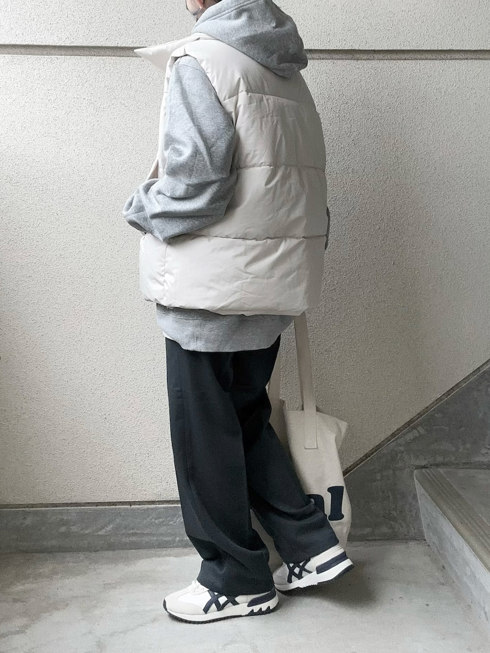 ホワイト系のダウンベスト、グレー系のスラックス、グレー系のパーカーを着用したレディースの冬コーディネートの3枚目の写真