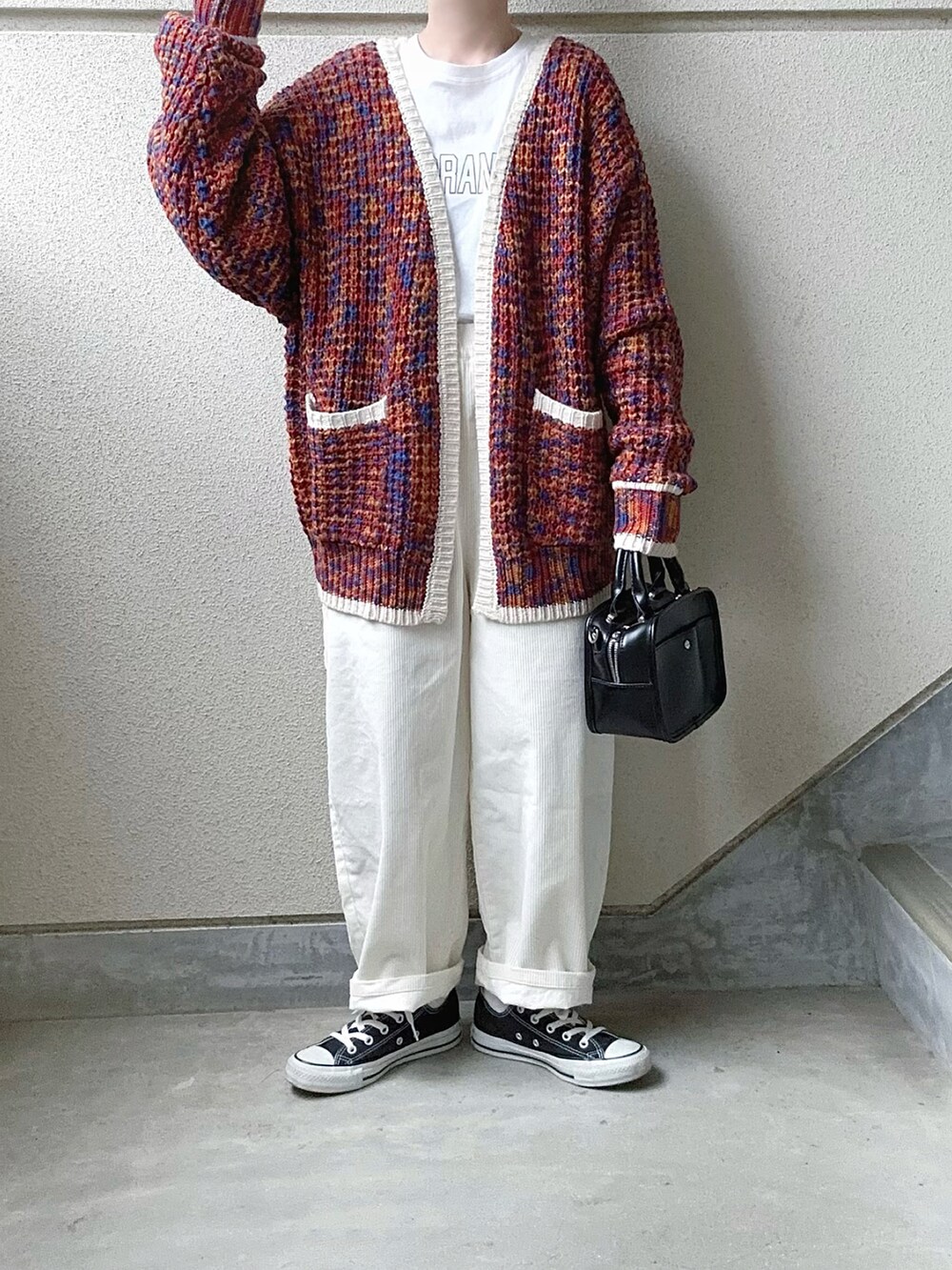 ホワイト系のパンツ、オレンジ系のカーディガン/ボレロ、ホワイト系のTシャツ/カットソーを着用したレディースの冬コーディネートの2枚目の写真