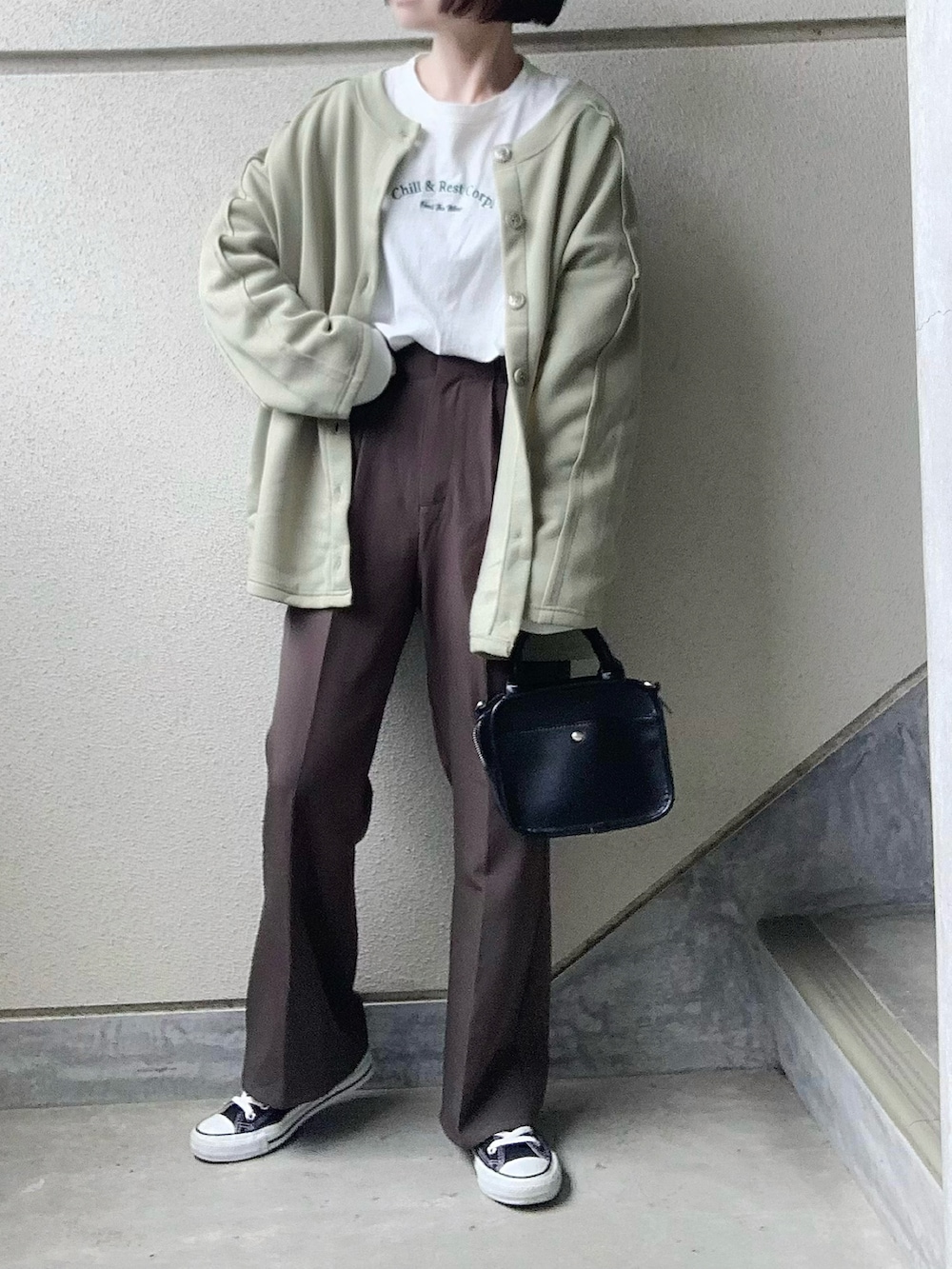 グリーン系のカーディガン/ボレロ、ホワイト系のTシャツ/カットソー、グレー系のスラックスを着用したレディースの冬コーディネートの2枚目の写真