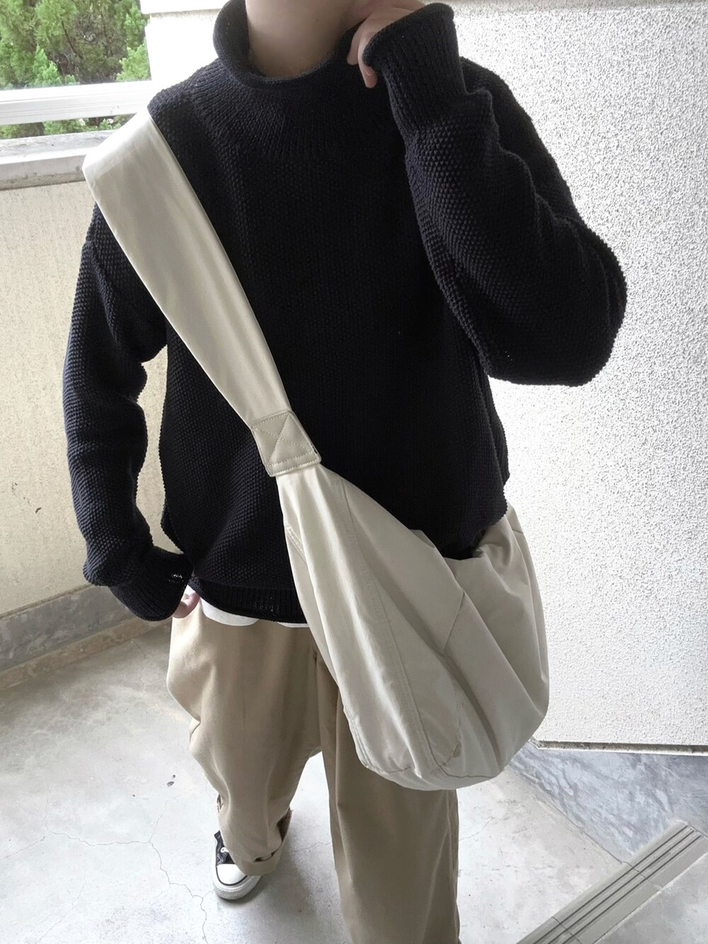 ブラック系のニット/セーター、ベージュ系のチノパンツ、ホワイト系のショルダーバッグを着用したレディースの秋コーディネートの4枚目の写真