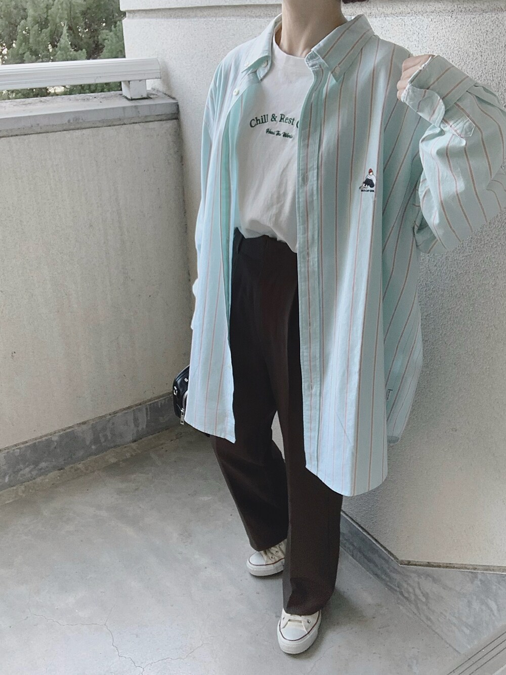 グリーン系のシャツ/ブラウス、グレー系のスラックス、ホワイト系のスニーカーを着用したレディースの冬コーディネートの2枚目の写真