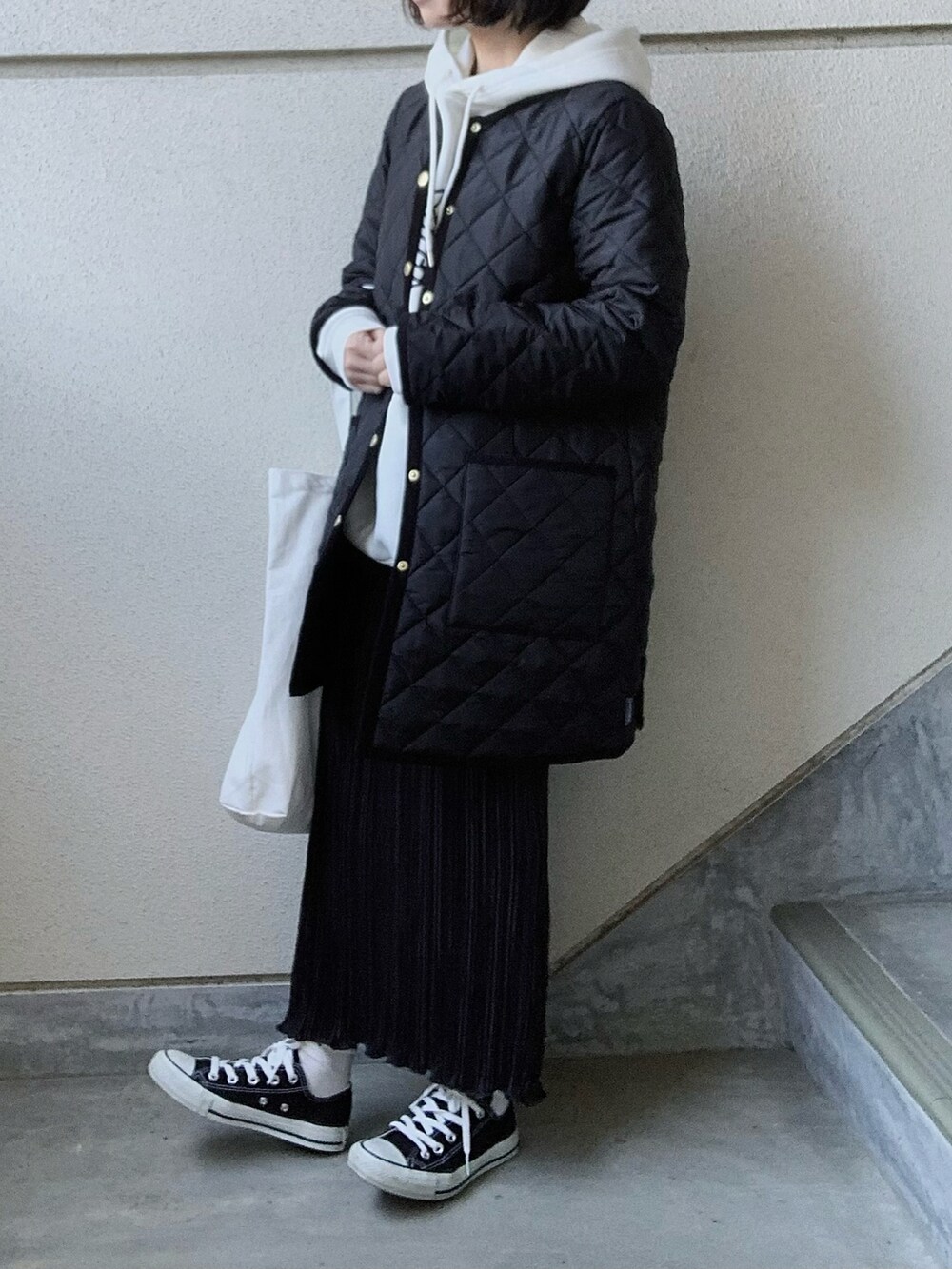 ブラック系のノーカラーコート、ホワイト系のパーカー、ホワイト系のトートバッグを着用したレディースの冬コーディネートの2枚目の写真