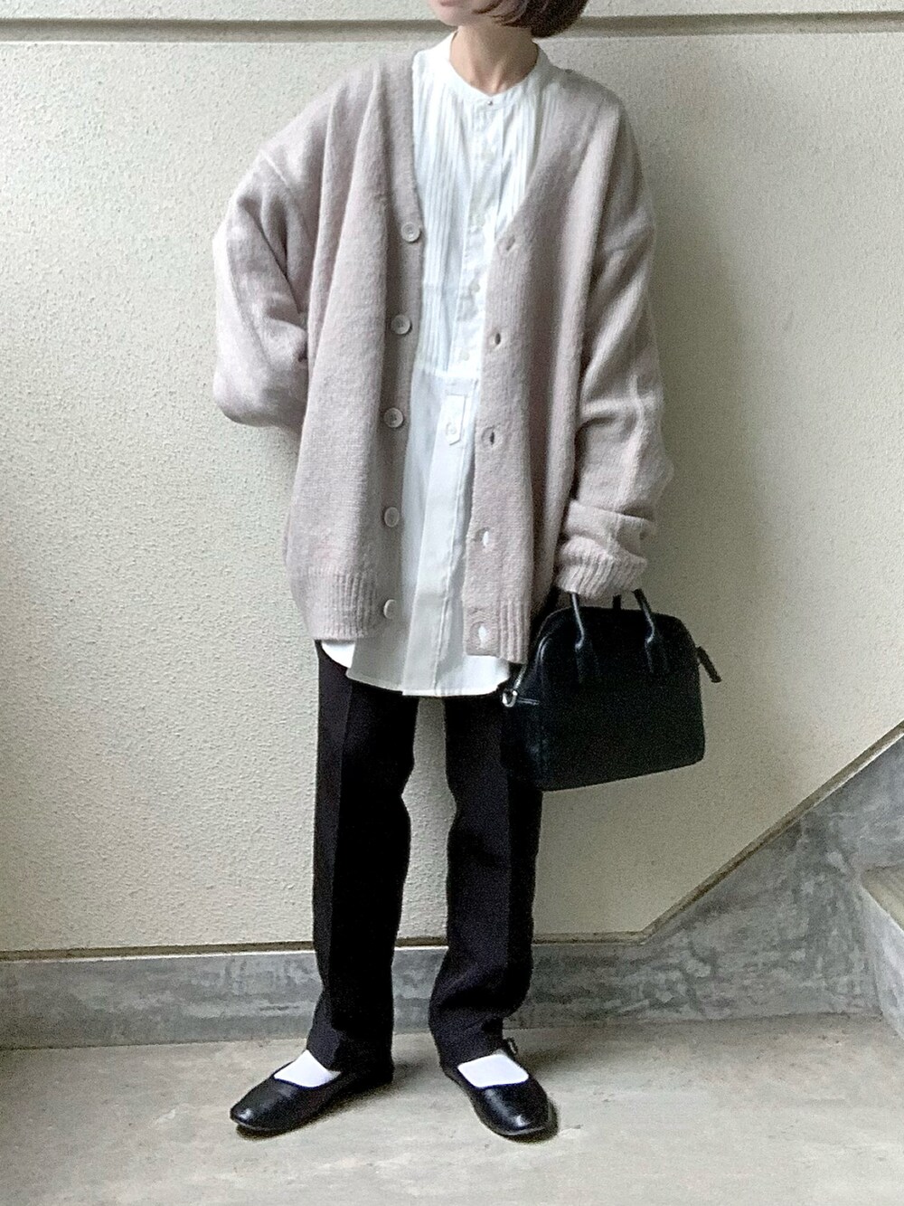 ベージュ系のカーディガン/ボレロ、ホワイト系のシャツ/ブラウス、ブラック系のスラックスを着用したレディースの秋コーディネートの2枚目の写真