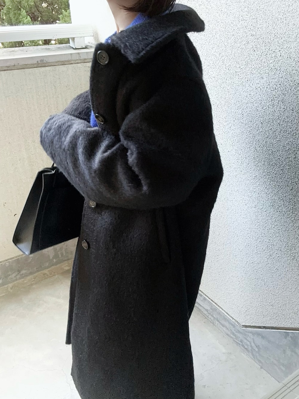 ブラック系のチェスターコート、ブルー系のニット/セーター、ブラック系のショルダーバッグを着用したレディースの秋コーディネートの5枚目の写真