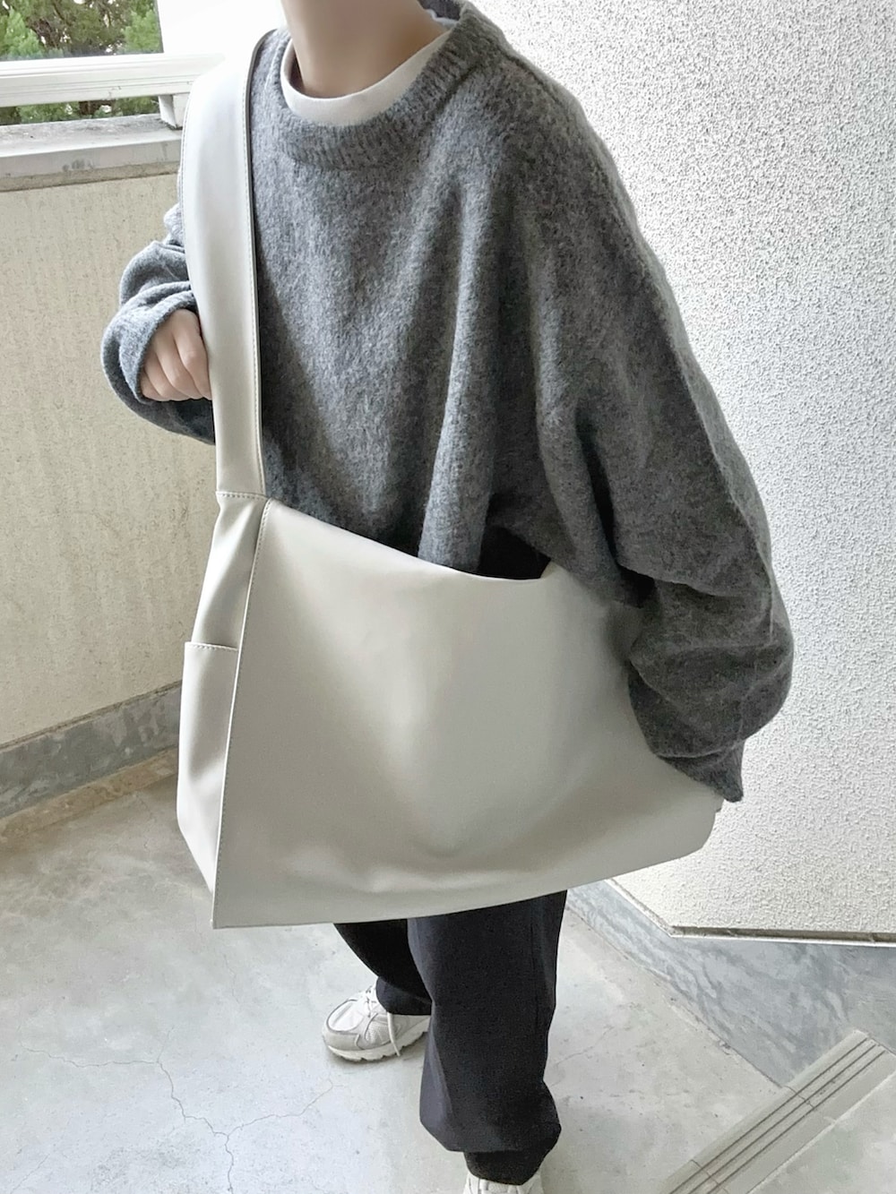 グレー系のニット/セーター、グレー系のショルダーバッグを着用したレディースの冬コーディネートの4枚目の写真