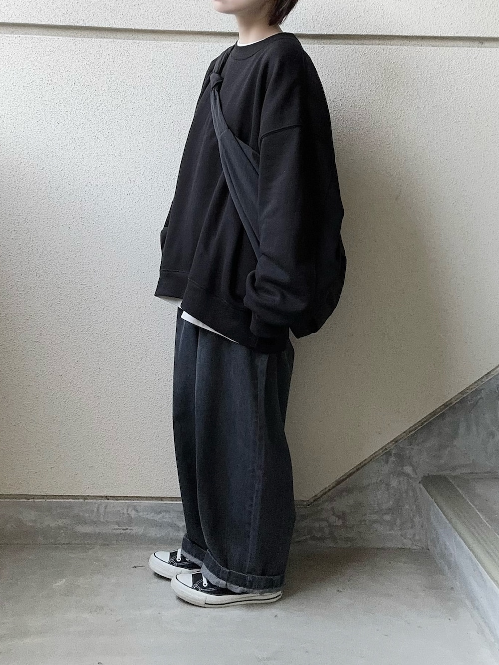 グレー系のデニムパンツ、ブラック系のスウェット、ホワイト系のTシャツ/カットソーを着用したレディースの秋コーディネートの2枚目の写真