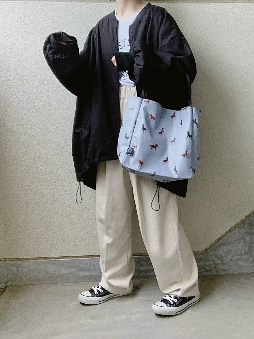 ブルー系のトートバッグ、ホワイト系のTシャツ/カットソー、ブラック系のブルゾンを着用したレディースの春コーディネートの3枚目の写真