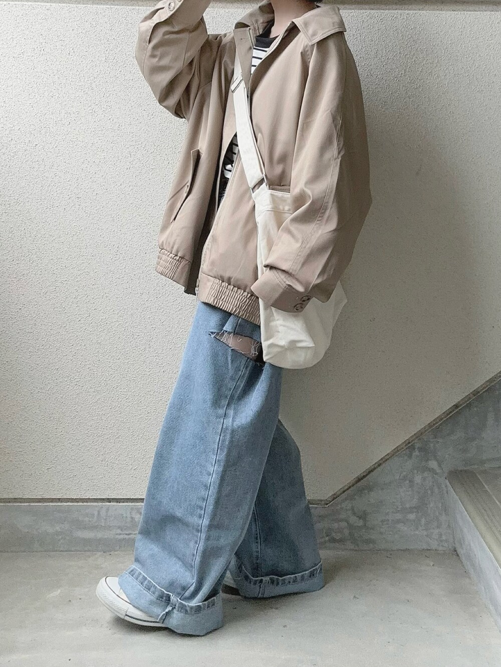 ブルー系のデニムパンツ、ベージュ系のトレンチコート、ブラック系のTシャツ/カットソーを着用したレディースの春コーディネートの3枚目の写真