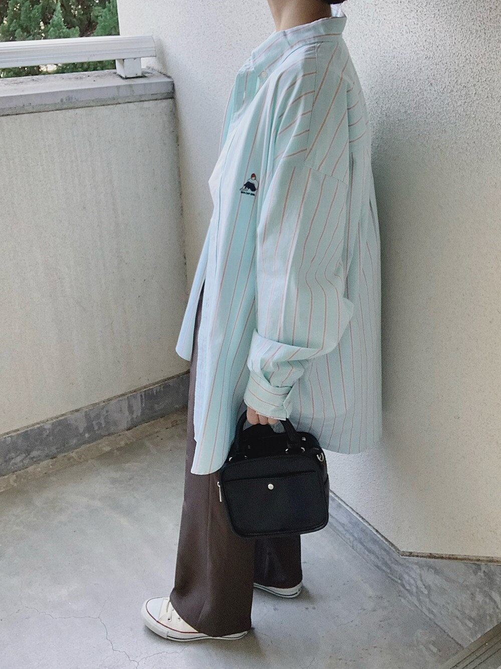 グリーン系のシャツ/ブラウス、グレー系のスラックス、ホワイト系のスニーカーを着用したレディースの冬コーディネートの3枚目の写真