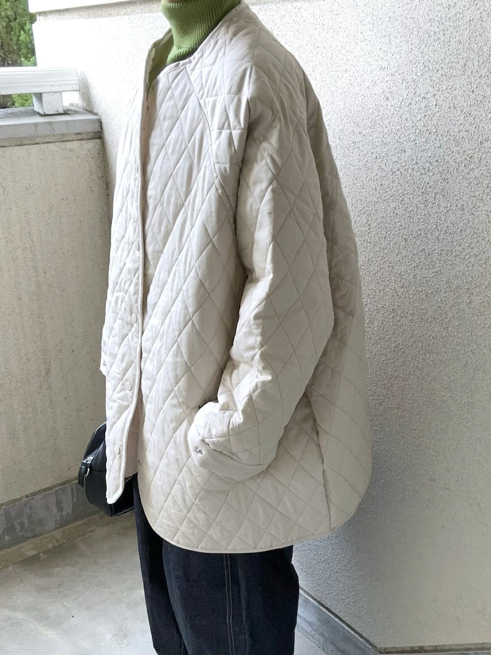 ホワイト系のノーカラージャケット、ブルー系のデニムパンツ、グリーン系のニット/セーターを着用したレディースの秋コーディネートの5枚目の写真