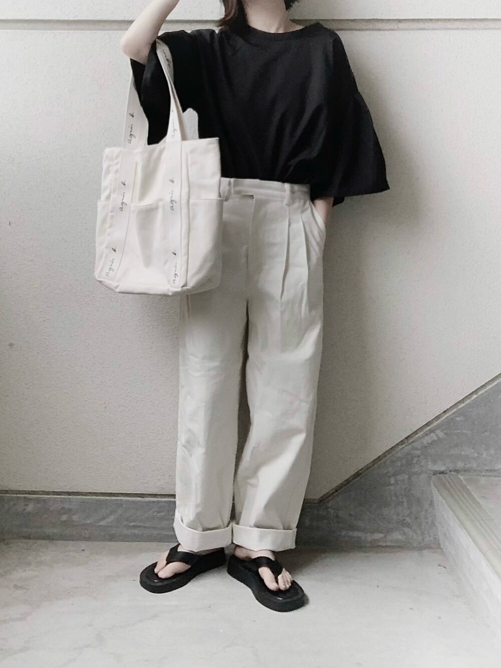 ブラック系のシャツ/ブラウス、ホワイト系のチノパンツ、ベージュ系のトートバッグを着用したレディースの春コーディネートの2枚目の写真