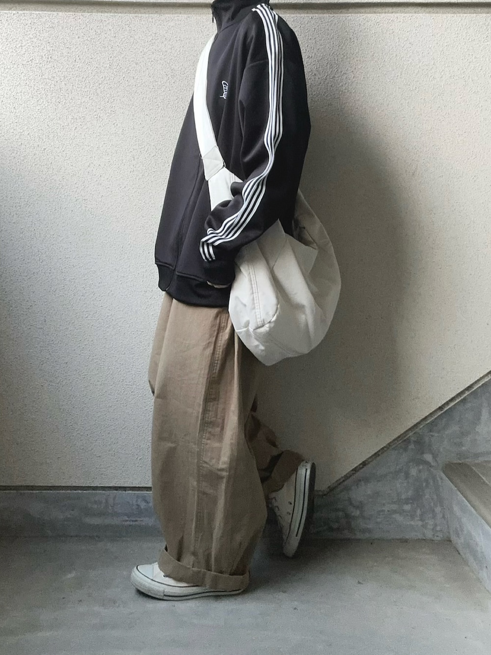 ブラック系のジャージ、ベージュ系のチノパンツを着用したレディースの春コーディネートの4枚目の写真