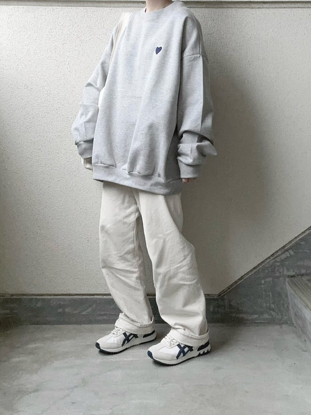 グレー系のスウェット、ホワイト系のデニムパンツ、ホワイト系のトートバッグを着用したレディースの冬コーディネートの3枚目の写真