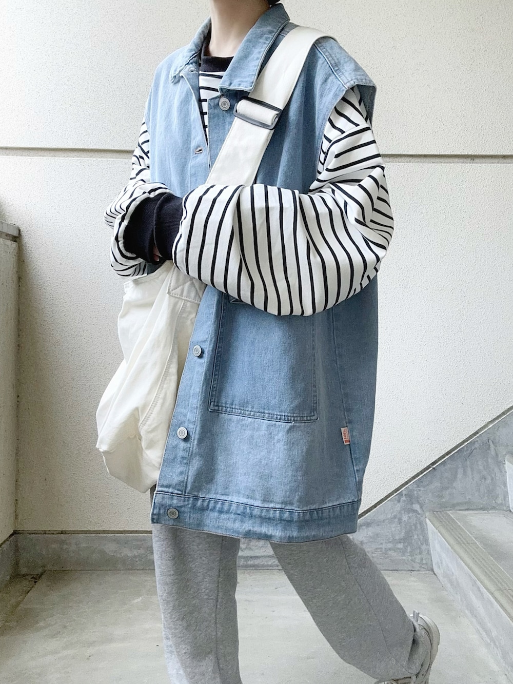 ブルー系のデニムジャケット、ブラック系のTシャツ/カットソー、グレー系のスウェットパンツを着用したレディースの春コーディネートの4枚目の写真