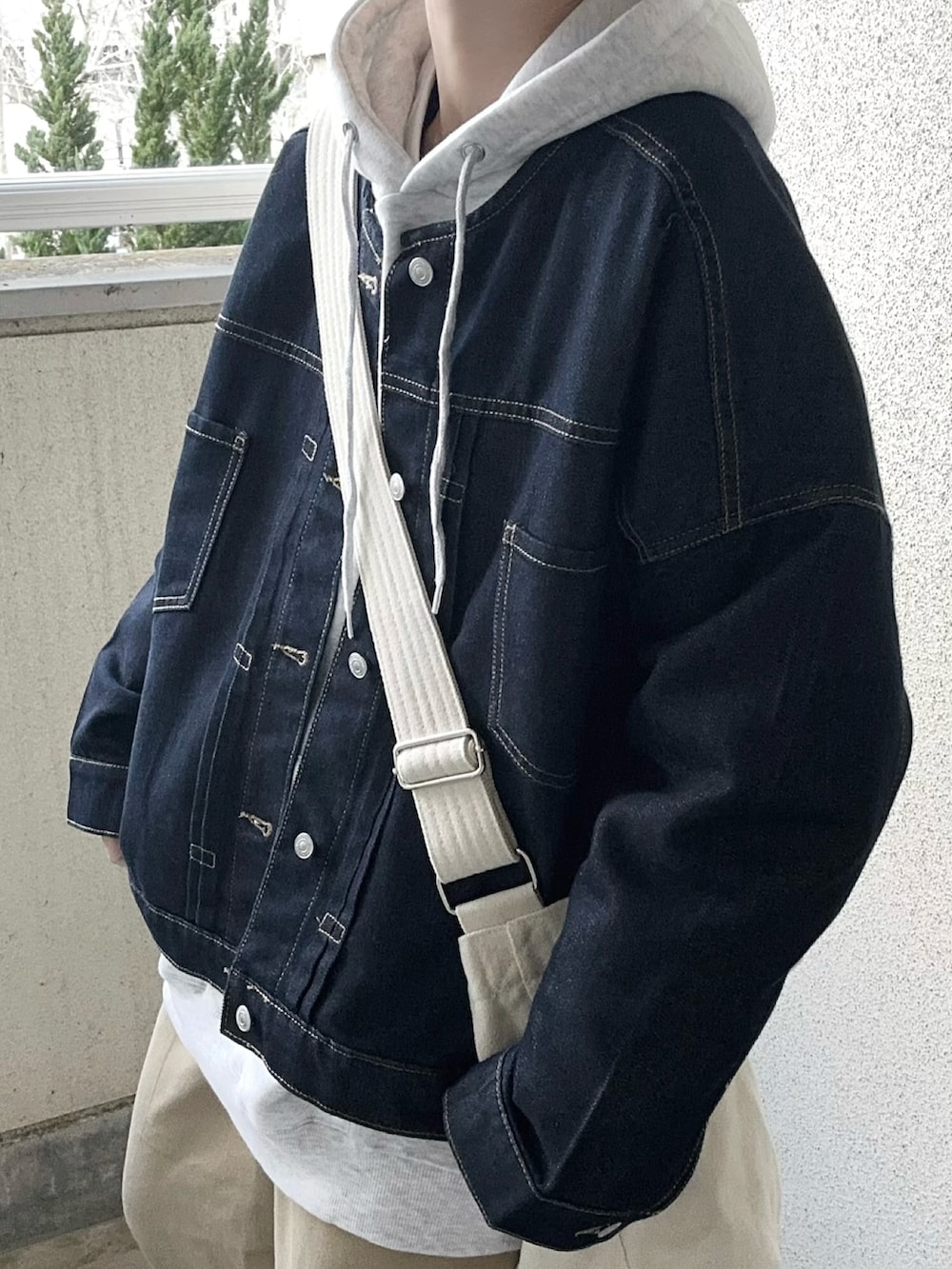 ブルー系のデニムジャケット、グレー系のパーカー、ホワイト系のショルダーバッグを着用したレディースの春コーディネートの3枚目の写真