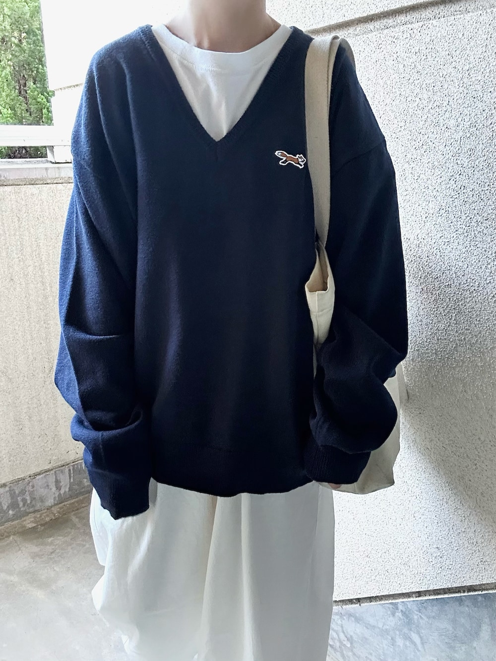 ブルー系のニット/セーター、ホワイト系のチノパンツ、ベージュ系のスニーカーを着用したレディースの秋コーディネートの4枚目の写真