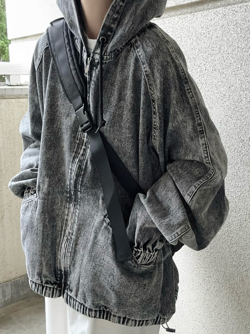 ブラック系のブルゾン、ブラック系のボディバッグ/ウエストポーチ、ホワイト系のチノパンツを着用したレディースの春コーディネートの4枚目の写真