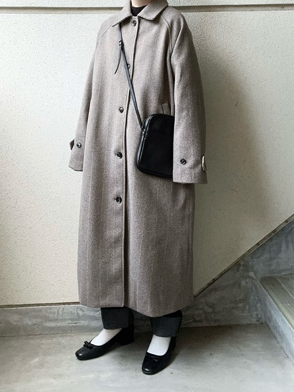 ブラウン系のステンカラーコート、ブルー系のデニムパンツ、ブラック系のショルダーバッグを着用したレディースの冬コーディネートの5枚目の写真