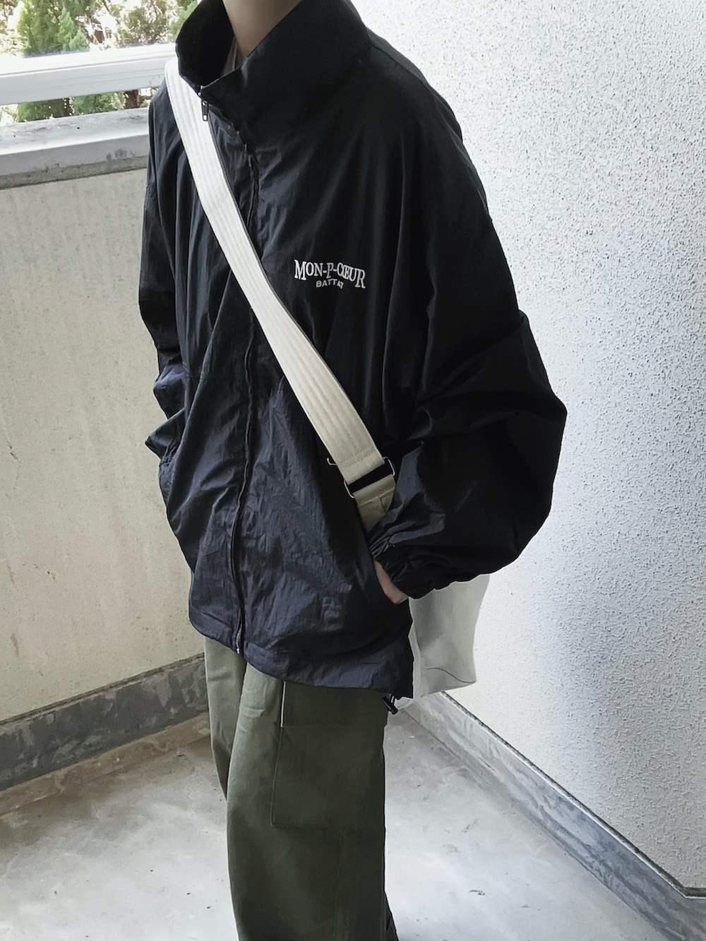 ブラック系のブルゾン、ホワイト系のショルダーバッグ、グリーン系のカーゴパンツを着用したレディースの秋コーディネートの5枚目の写真