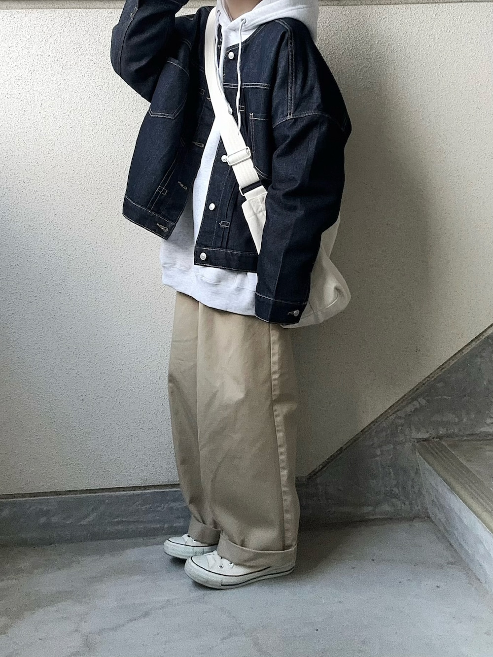 ブルー系のデニムジャケット、グレー系のパーカー、ホワイト系のショルダーバッグを着用したレディースの春コーディネートの2枚目の写真