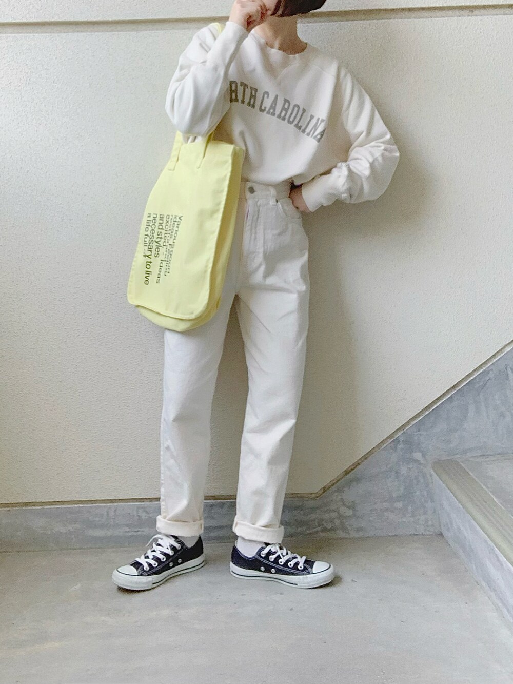 ホワイト系のスウェット、ホワイト系のデニムパンツ、イエロー系のトートバッグを着用したレディースの春コーディネートの2枚目の写真