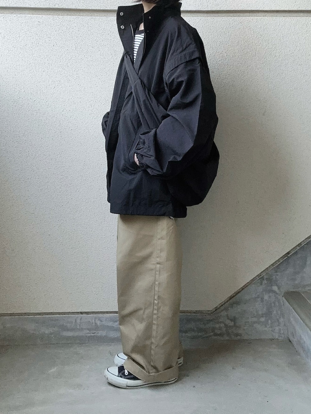 ブラック系のブルゾン、ブラック系のTシャツ/カットソー、ベージュ系のチノパンツを着用したレディースの春コーディネートの5枚目の写真