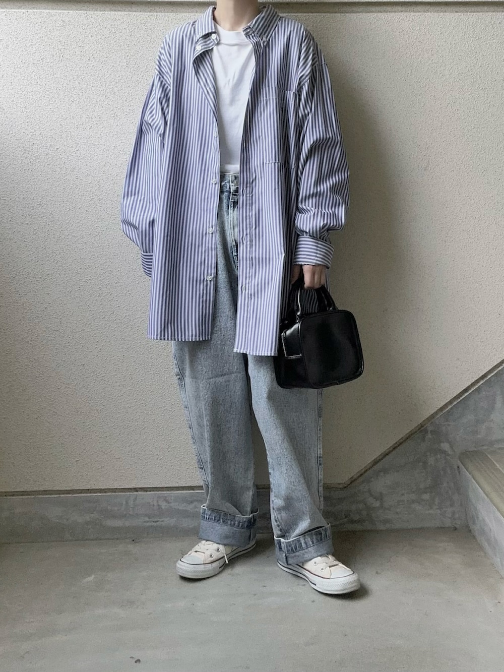 ブルー系のデニムパンツ、ホワイト系のベスト、ホワイト系のスニーカーを着用したレディースの春コーディネートの3枚目の写真