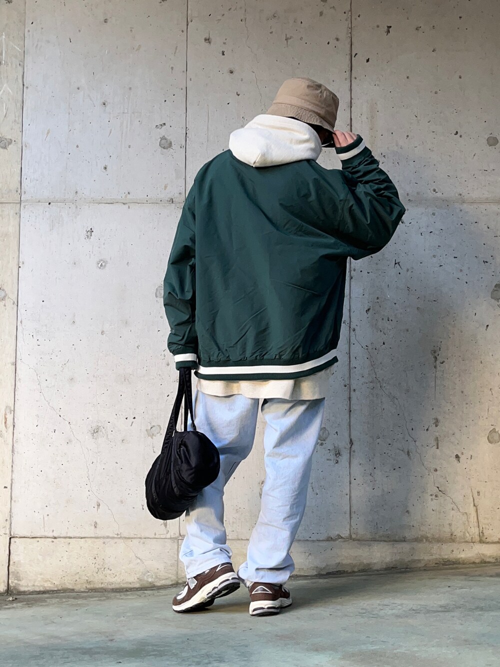 ホワイト系のパーカー、ブルー系のデニムパンツ、ブラック系のボストンバッグを着用したメンズの冬コーディネートの2枚目の写真