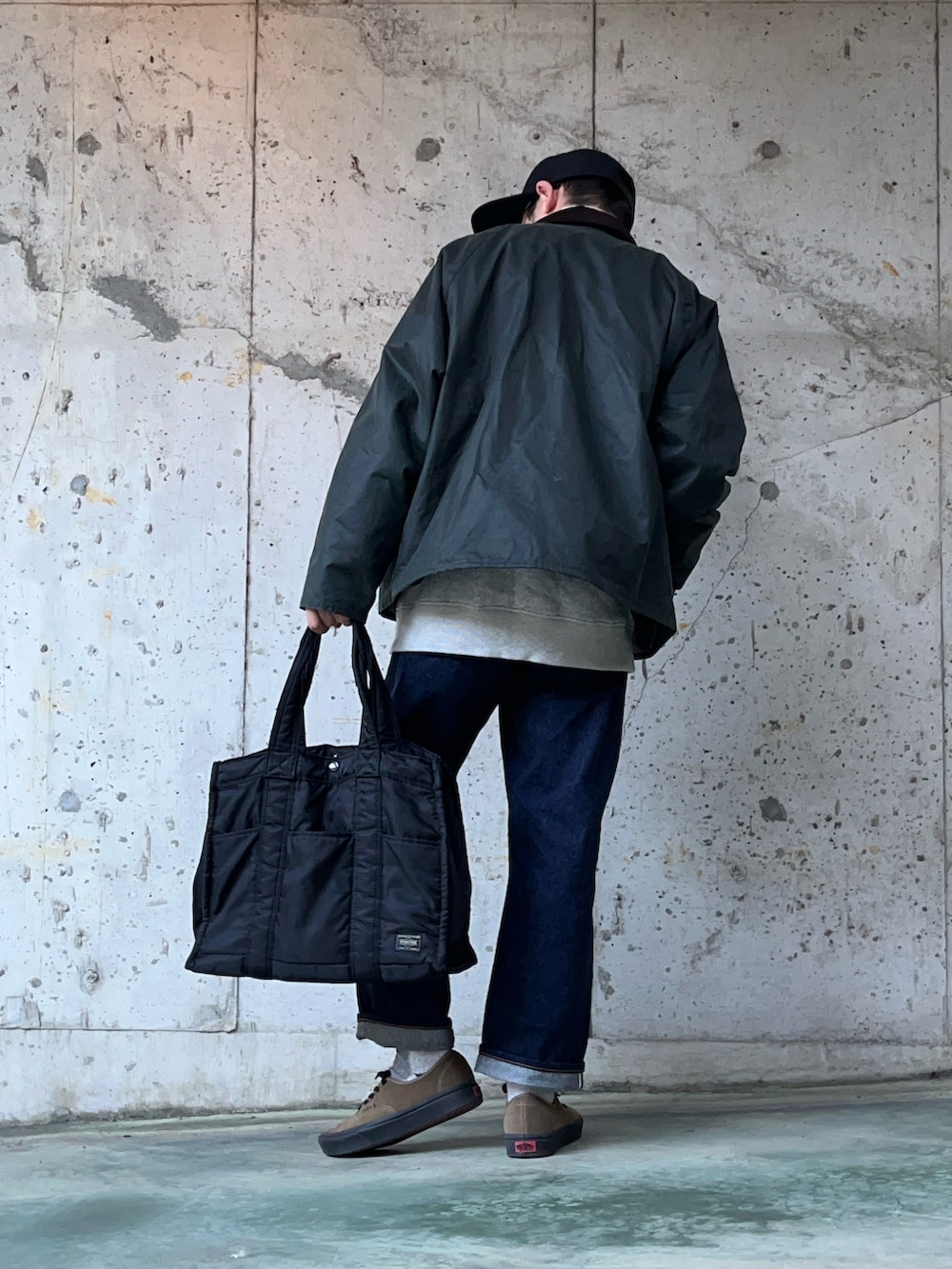 グリーン系のブルゾン、ブルー系のデニムパンツ、ブラック系のトートバッグを着用したメンズの冬コーディネートの2枚目の写真