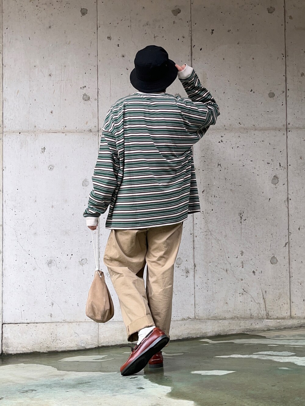 グリーン系のTシャツ/カットソー、ベージュ系のチノパンツ、ベージュ系のハンドバッグを着用したメンズの春コーディネートの2枚目の写真