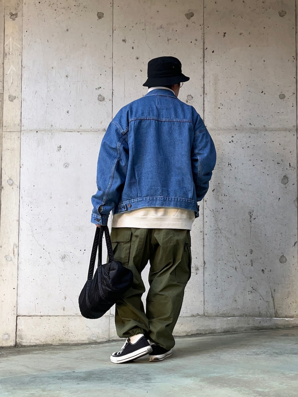 ブルー系のデニムジャケット、グリーン系のカーゴパンツ、ブラック系のボストンバッグを着用したメンズの冬コーディネートの2枚目の写真