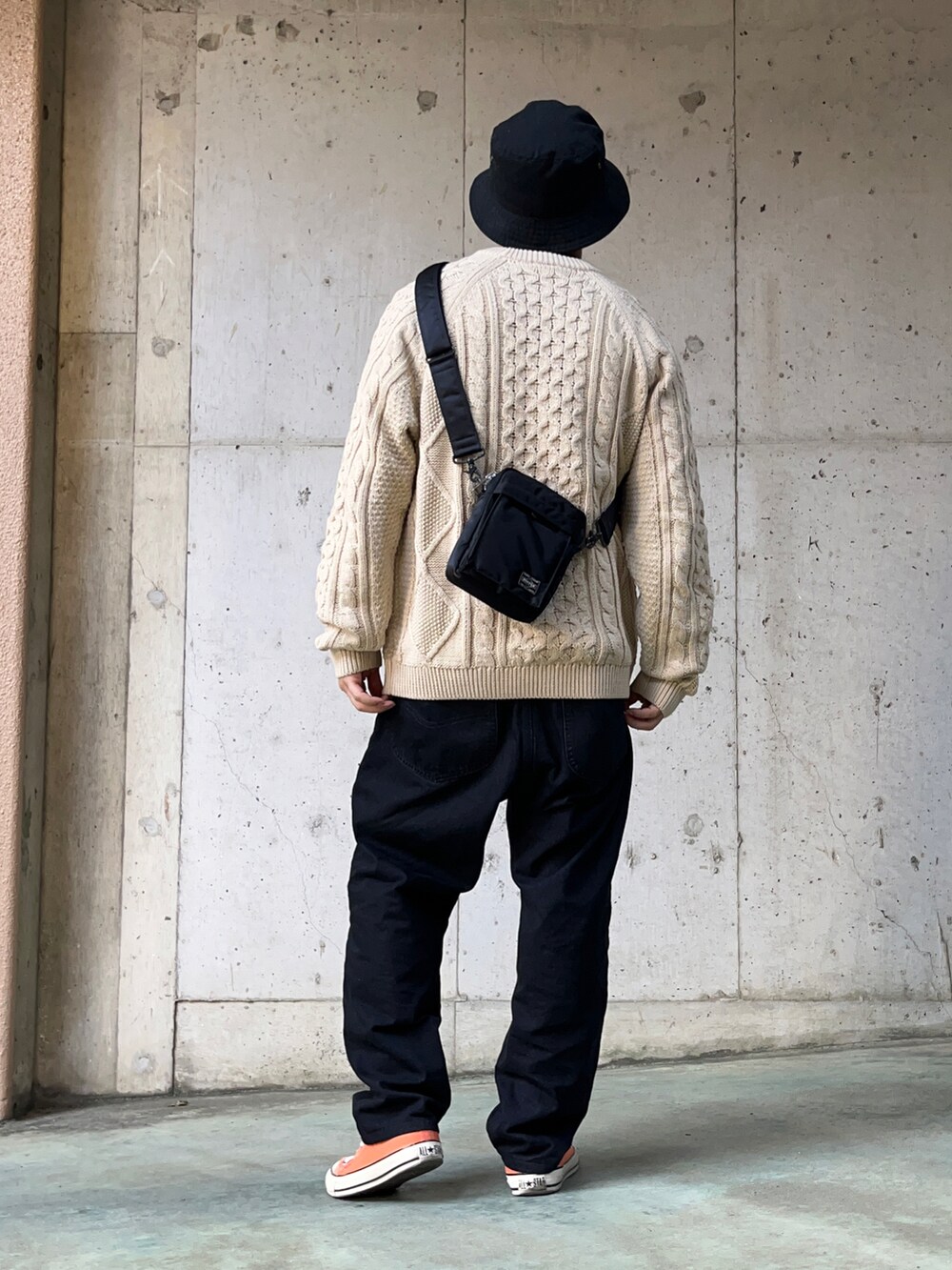 ベージュ系のニット/セーター、ブラック系のデニムパンツ、オレンジ系のスニーカーを着用したメンズの秋コーディネートの3枚目の写真