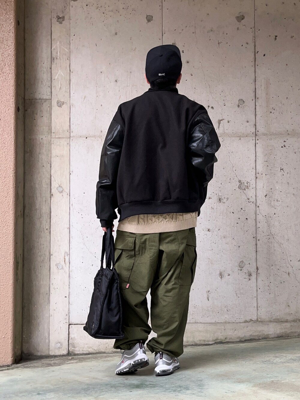ブラック系のスタジャン、ベージュ系のニット/セーター、グリーン系のカーゴパンツを着用したメンズの冬コーディネートの2枚目の写真
