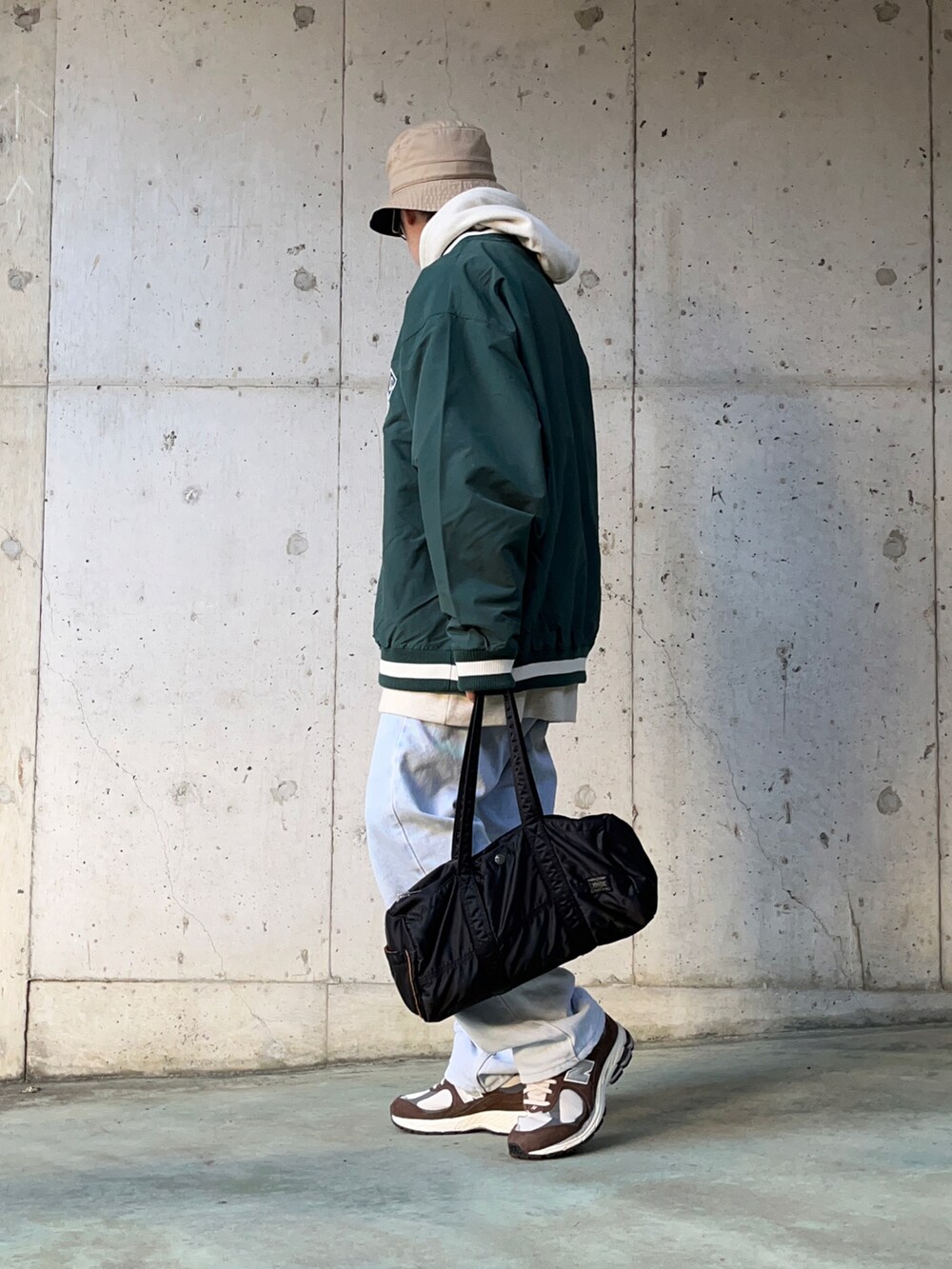 ホワイト系のパーカー、ブルー系のデニムパンツ、ブラック系のボストンバッグを着用したメンズの冬コーディネートの3枚目の写真