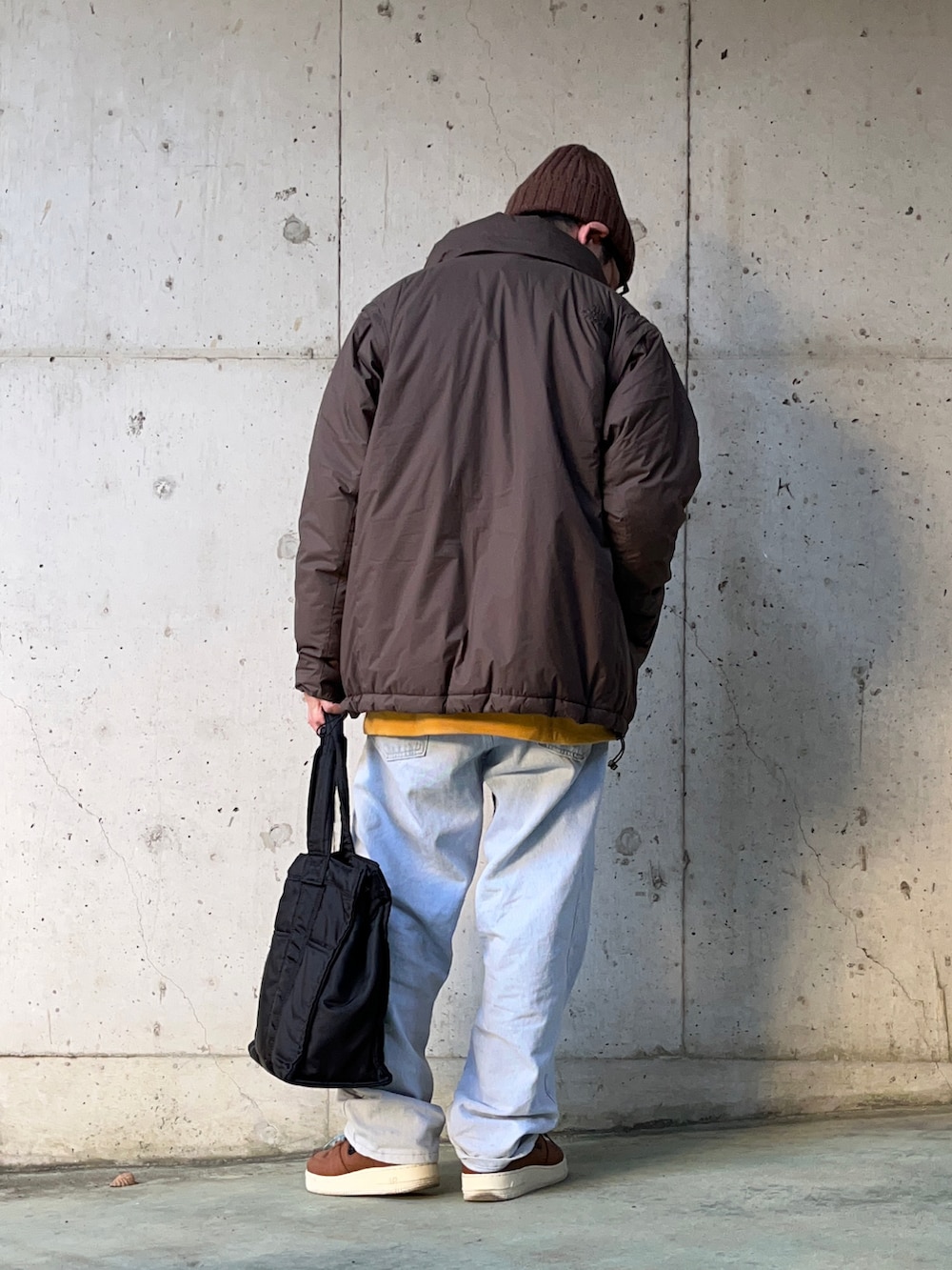 ブラウン系のその他アウター、ブルー系のデニムパンツ、ブラック系のトートバッグを着用したメンズの冬コーディネートの2枚目の写真