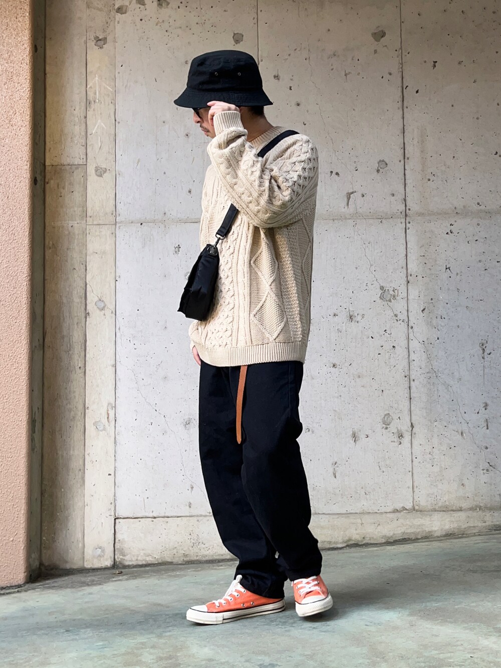 ベージュ系のニット/セーター、ブラック系のデニムパンツ、オレンジ系のスニーカーを着用したメンズの秋コーディネートの2枚目の写真