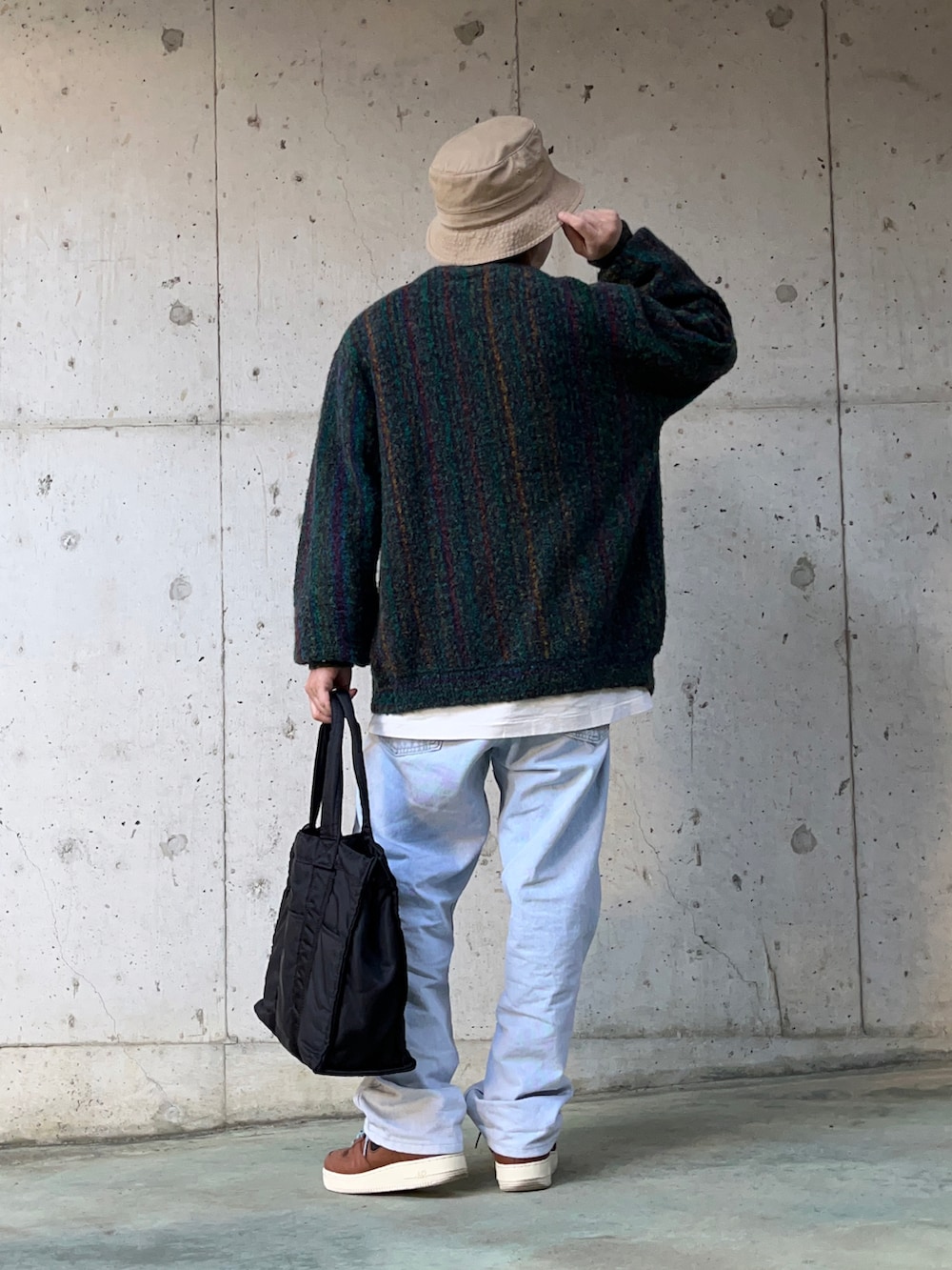 グリーン系のカーディガン/ボレロ、ブルー系のデニムパンツ、ブラック系のトートバッグを着用したメンズの冬コーディネートの2枚目の写真