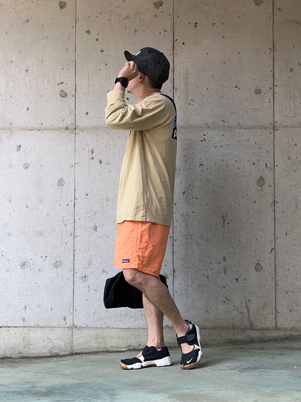 ベージュ系のTシャツ/カットソー、オレンジ系のその他パンツ、ブラック系のボストンバッグを着用したメンズの夏コーディネートの2枚目の写真