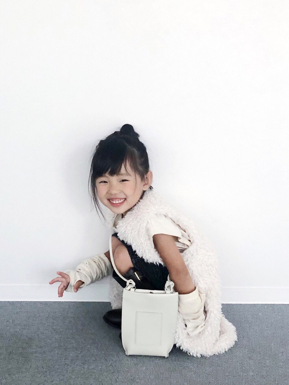 ブラウン系のブーツ、ホワイト系のショルダーバッグ、ホワイト系のベストを着用したキッズの秋コーディネートの3枚目の写真