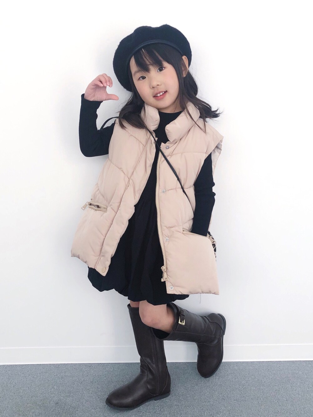 ブラウン系のブーツ、ブラック系のトートバッグ、ブラック系のワンピースを着用したキッズの冬コーディネートの2枚目の写真