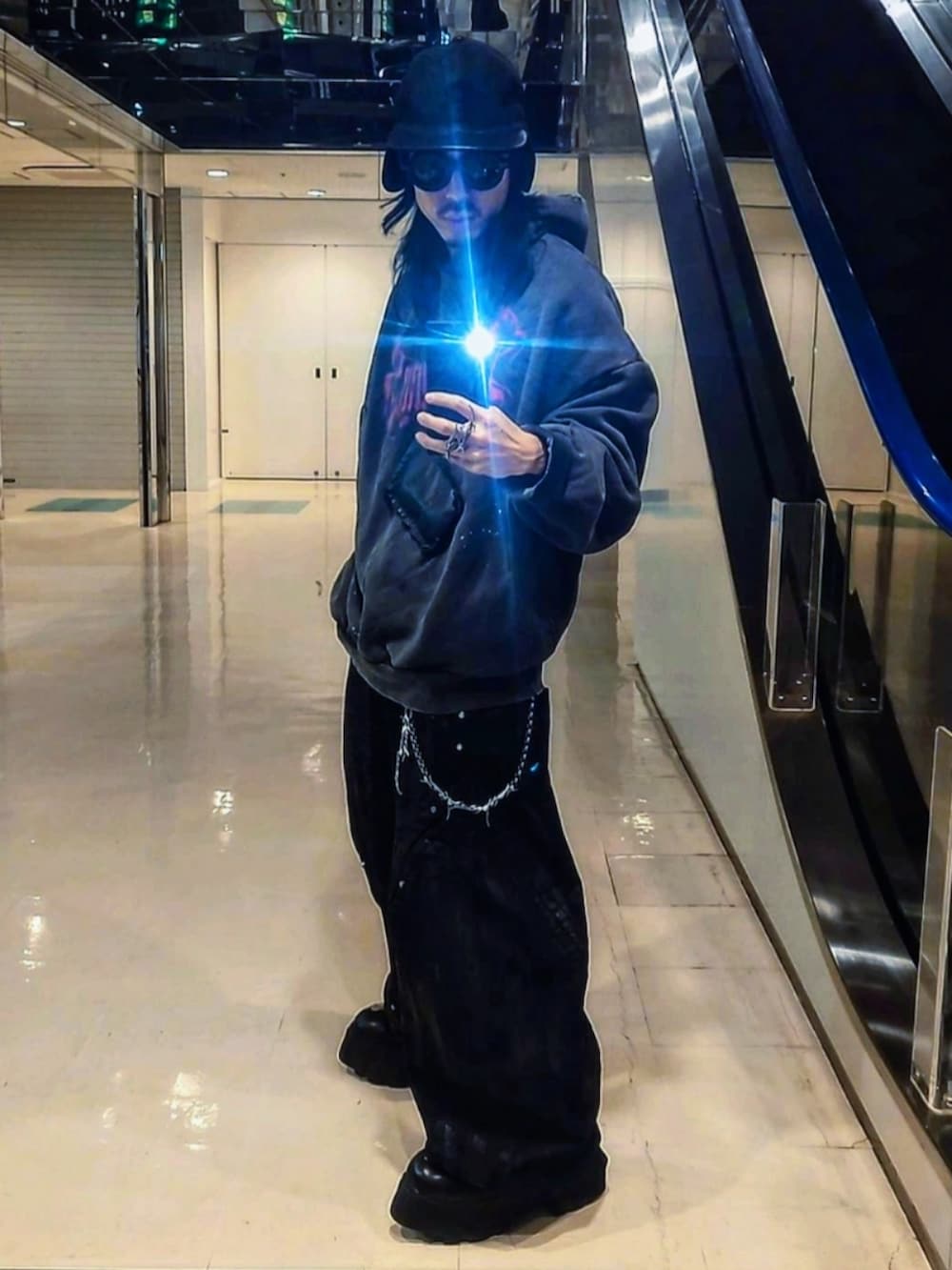 グレー系のパーカー、ブラック系のデニムパンツ、ブラック系のブーツを着用したメンズの春コーディネートの3枚目の写真